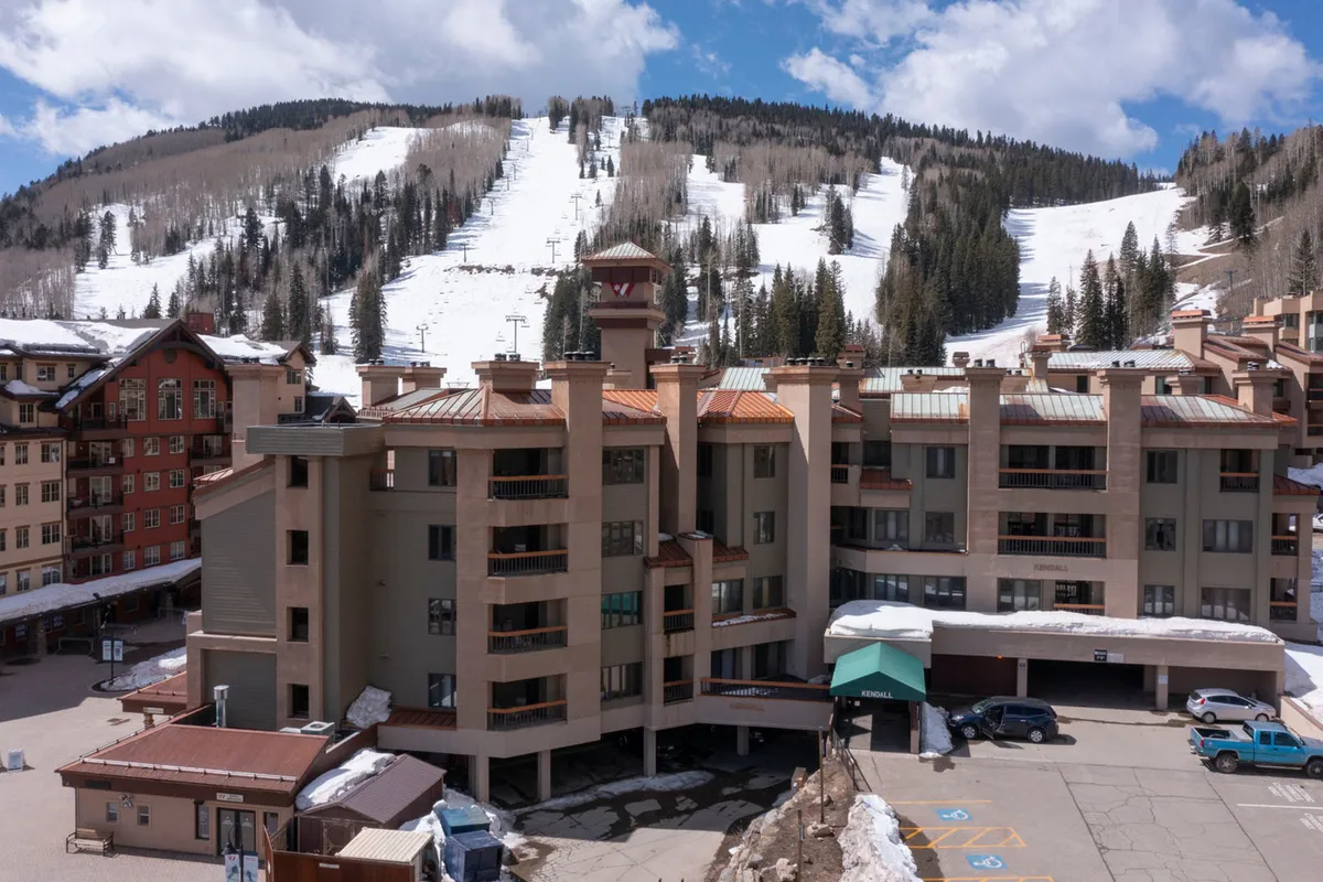 This image captures a multi-story lodge set against a dramatic mountain backdrop, with snow-covered slopes inviting visitors to ski or snowboard. The scene is alive with the energy of winter sports and the cozy allure of the lodge, suggesting both adventure and relaxation are close at hand.